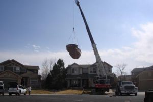 Photo of a Crane Lifting a Pool Over a House